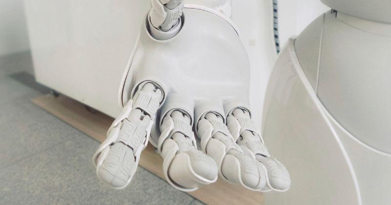 A robotic hand of a white robot reaching out